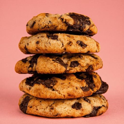 A stack of five warm Bakendales chocolate chip cookies, with visible melted chocolate chips.