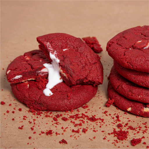 Twelve Bakendales red velvet cookies, showing their rich red color and visible white chocolate chips.
