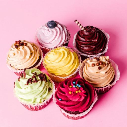 A variety of colorful Bakendales cupcakes, with different frosting designs and sprinkles.