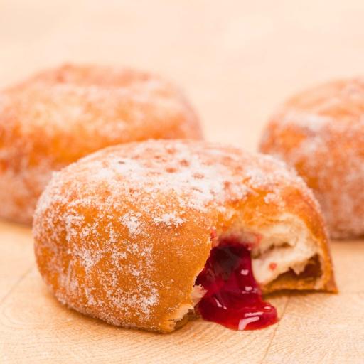 Bakendales doughnuts, with a dusting of sugar and a visible, creamy filling oozing from the side.