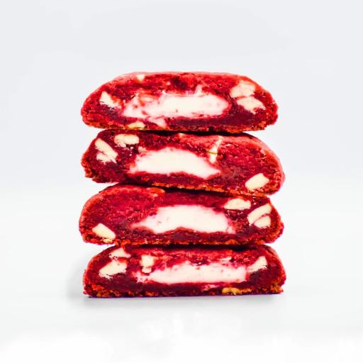 A cross-section of a Bakendales red velvet cookies, with visible white chocolate chips melted into the rich, red dough